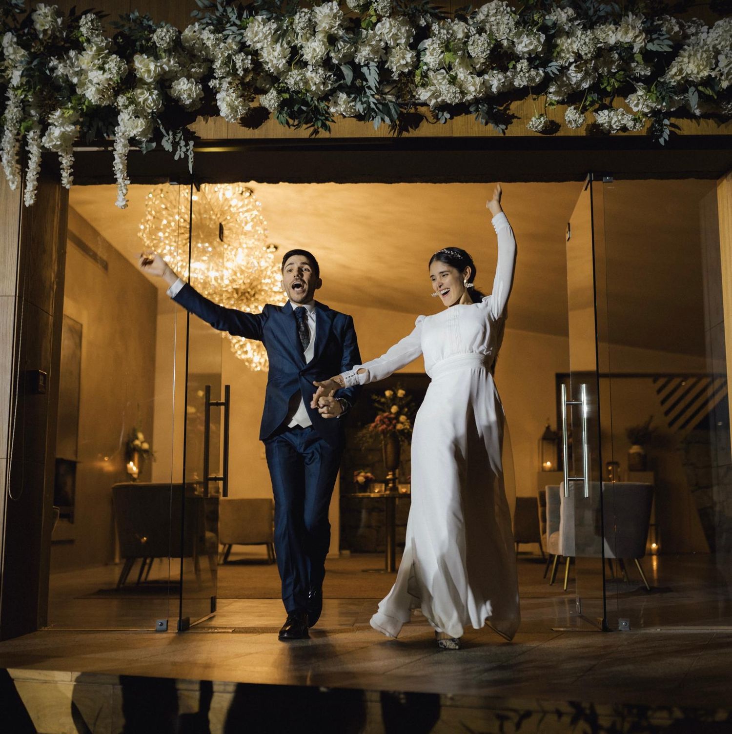 Wedding couple dances together under romantic floral decor and warm lighting.