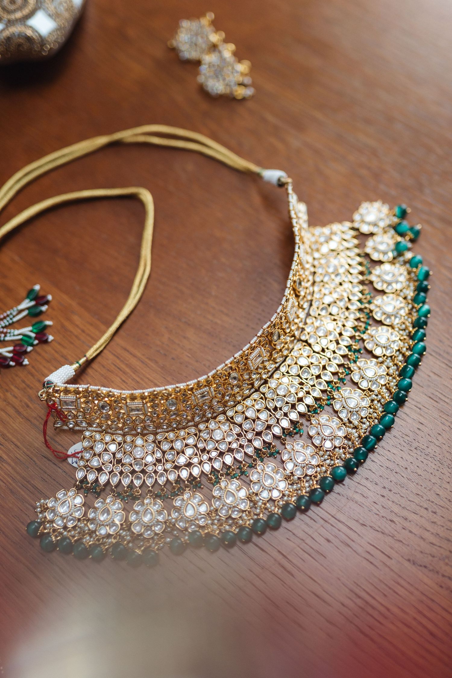 Stunning crystal and emerald statement necklace with intricate floral design on wooden surface.