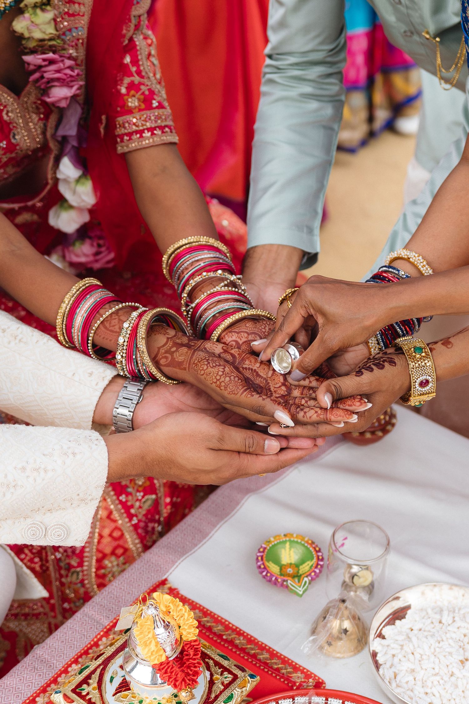 Close-up of hands with mehndi and bangles during a traditional Indian wedding ceremony ritual.