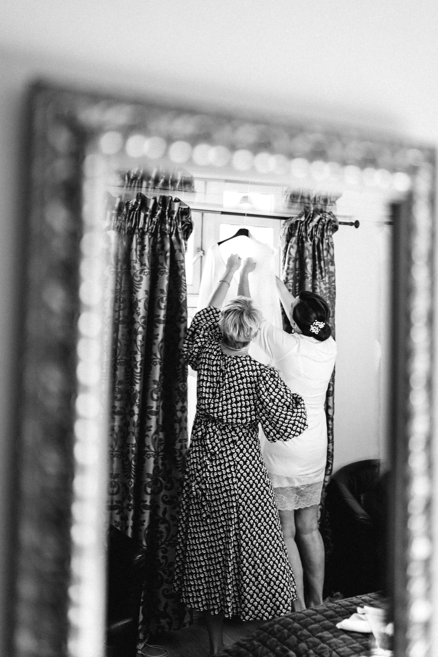 Black and white image of figures reflected in mirrors with polka dot patterns visible.