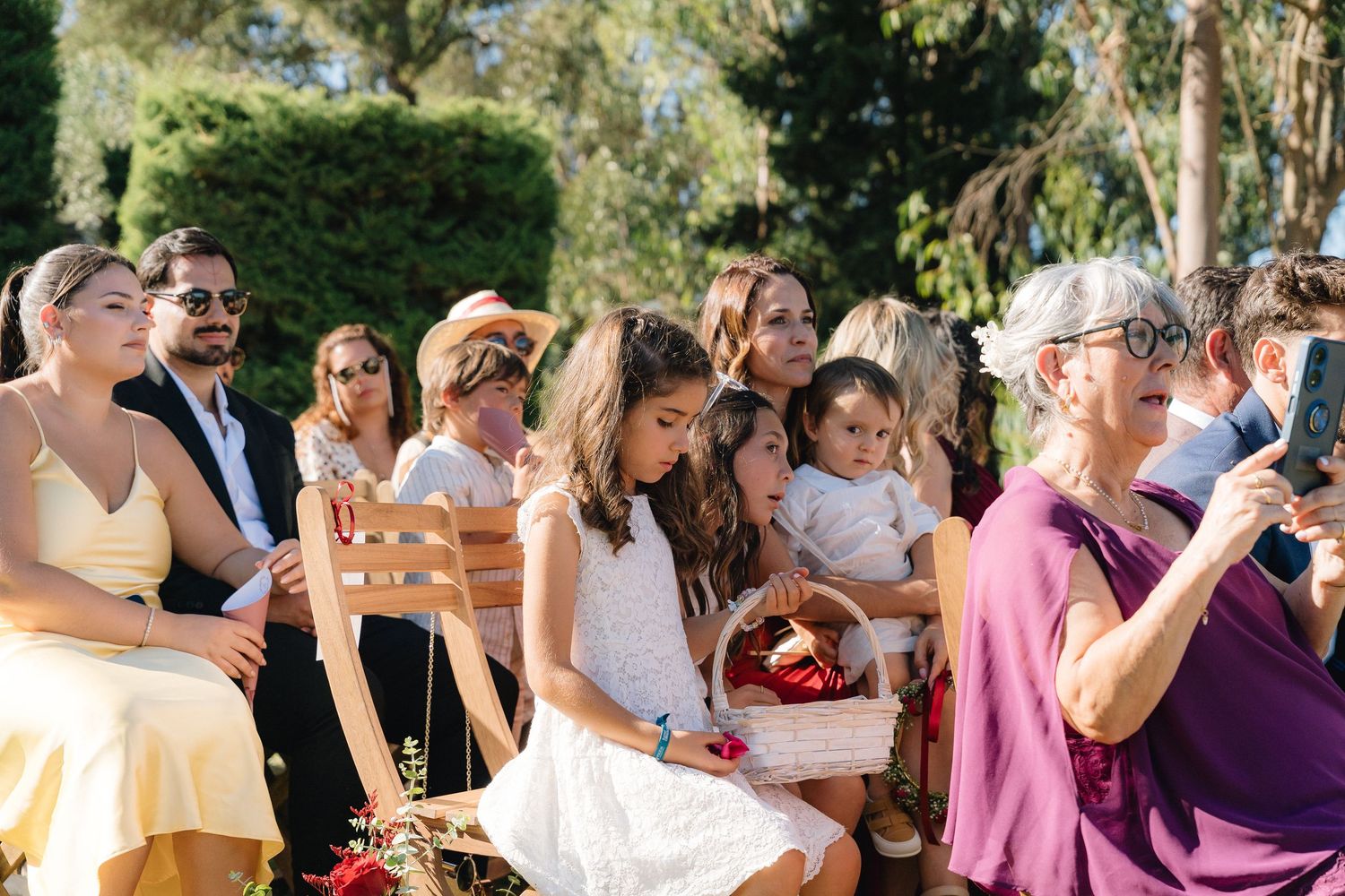 Wedding guests celebrate outdoors during a sunny summer celebration.