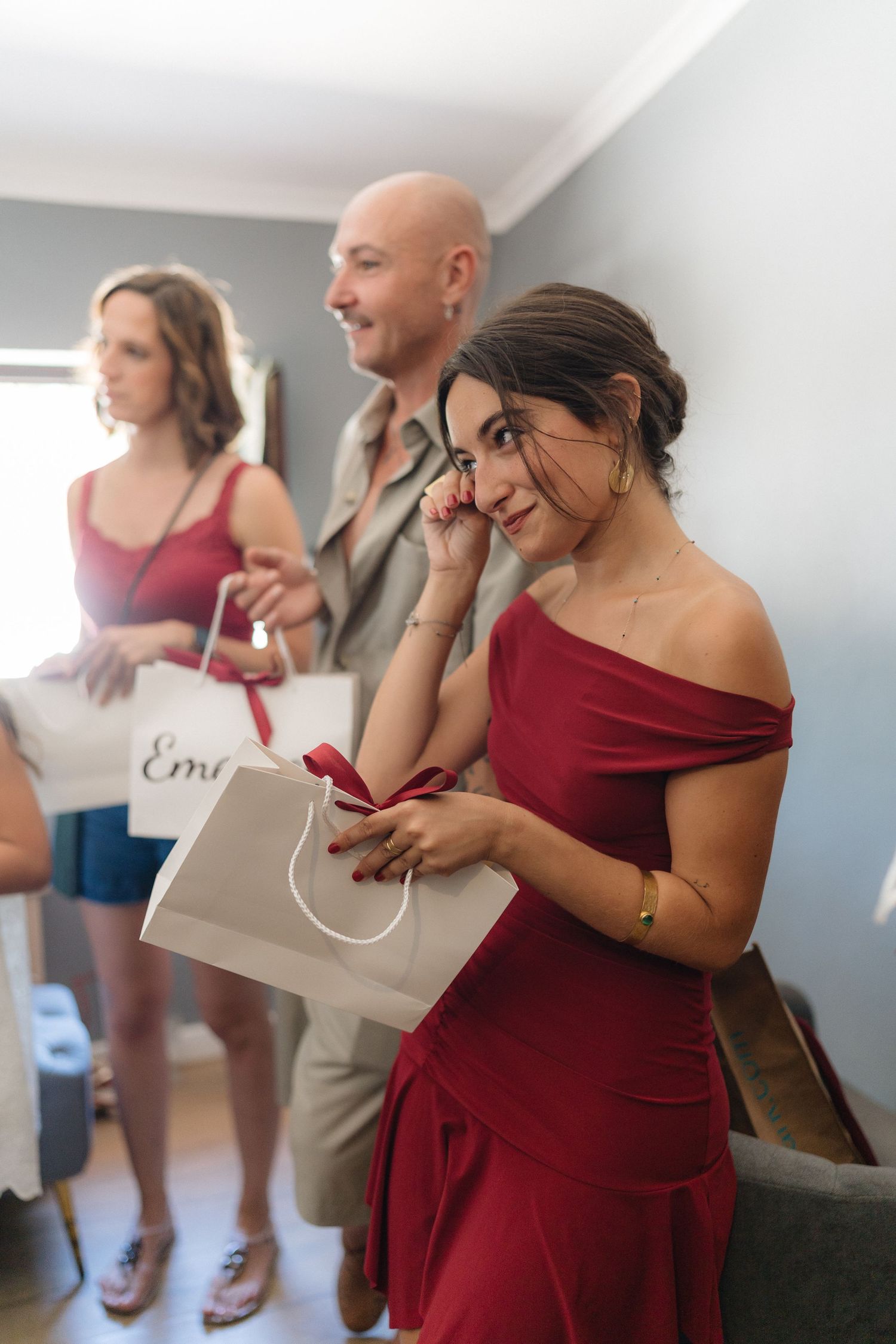Wedding party members in burgundy dresses opening special gift boxes.