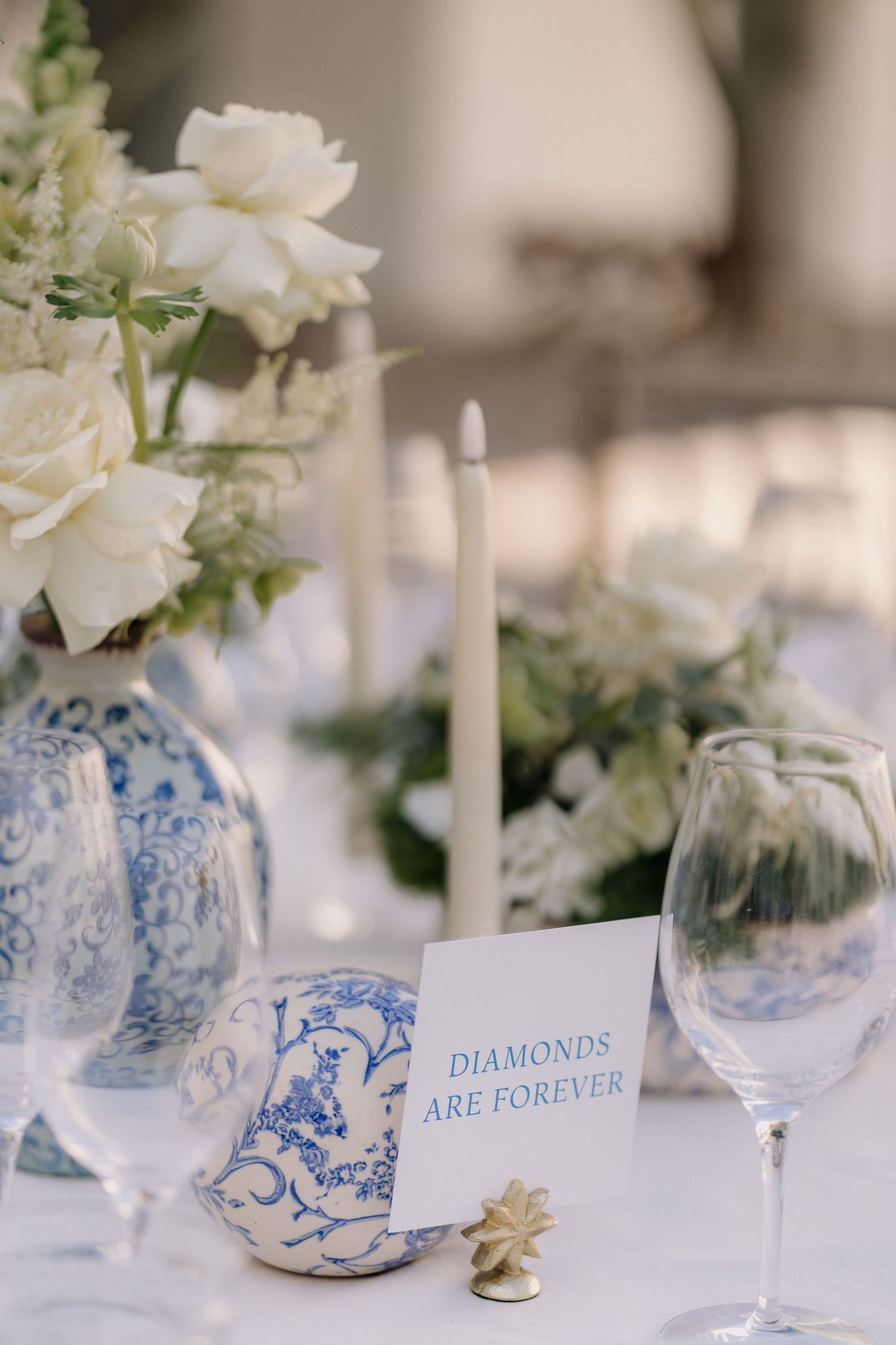 Wedding table decor featuring blue and white china patterns with white roses and place cards.