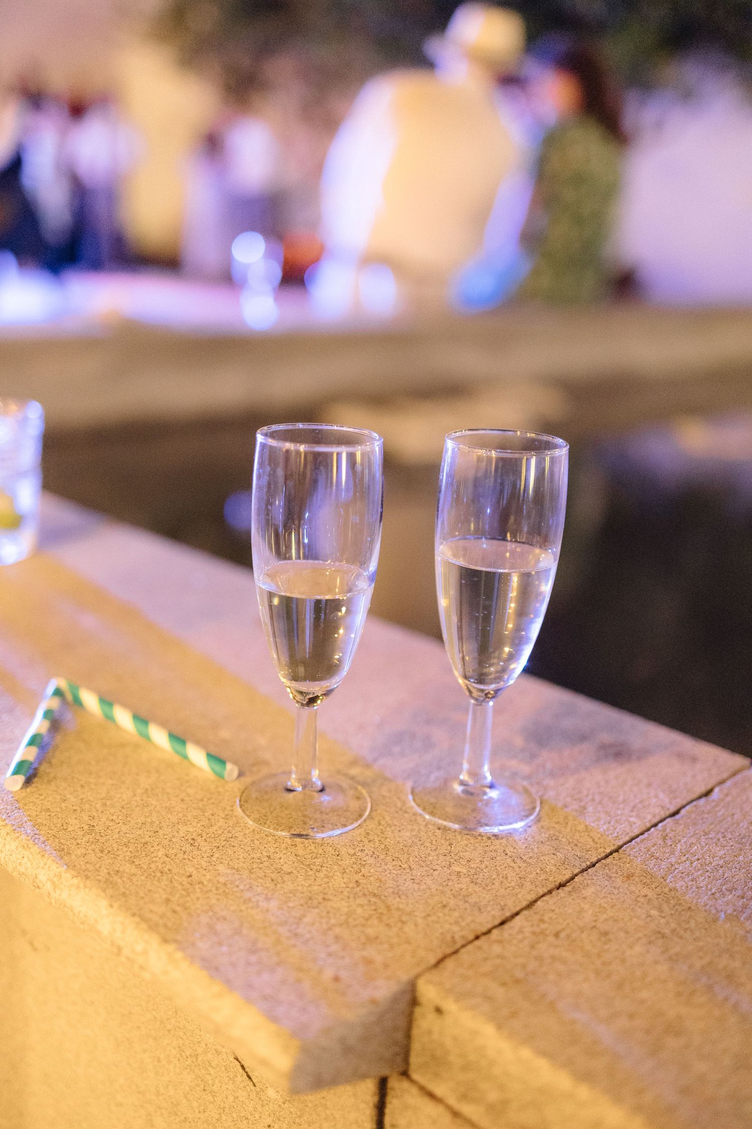 Champagne glasses lined up on a textured surface with ambient lighting in the background.