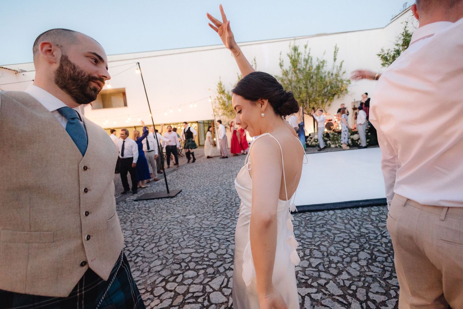 Wedding guests dancing and celebrating at outdoor courtyard reception.