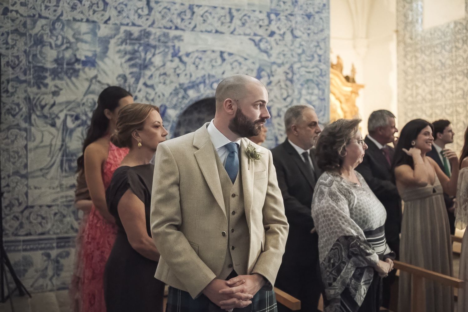 Wedding guests gathered in a chapel with traditional blue and white Portuguese azulejo tile walls.