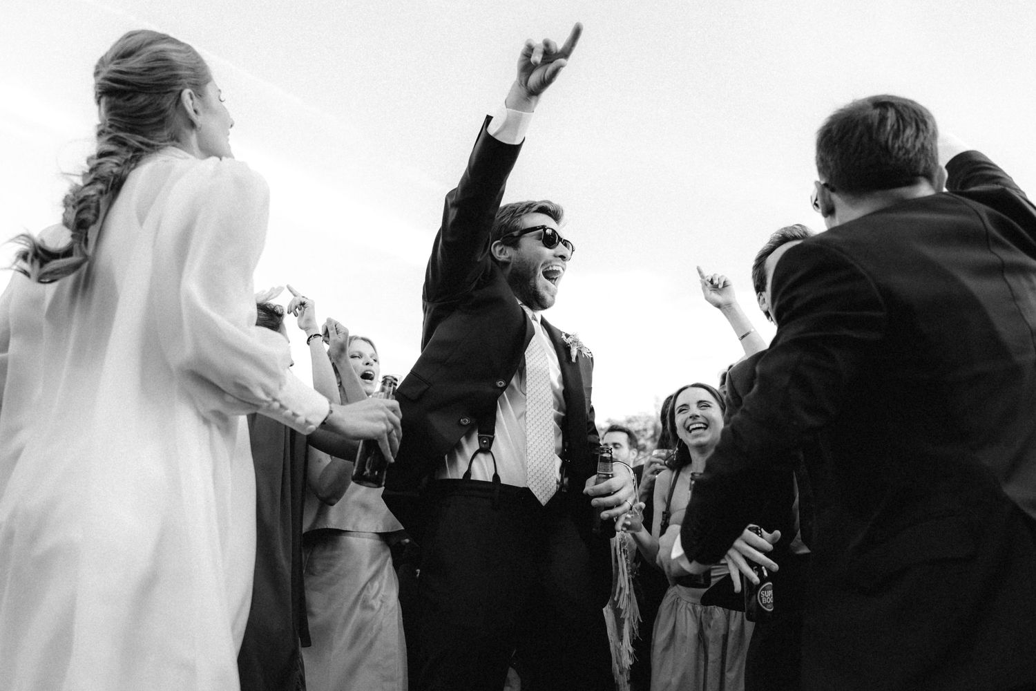 Candid black and white celebration shots of wedding party dancing.