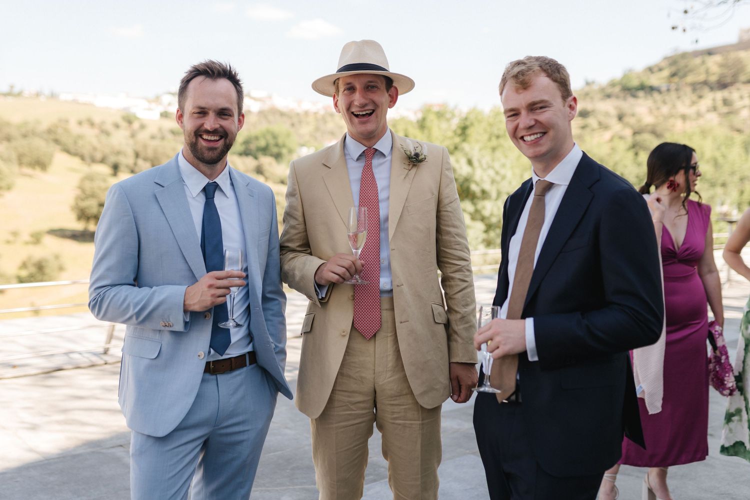 Wedding guests in formal attire socializing at an outdoor event.