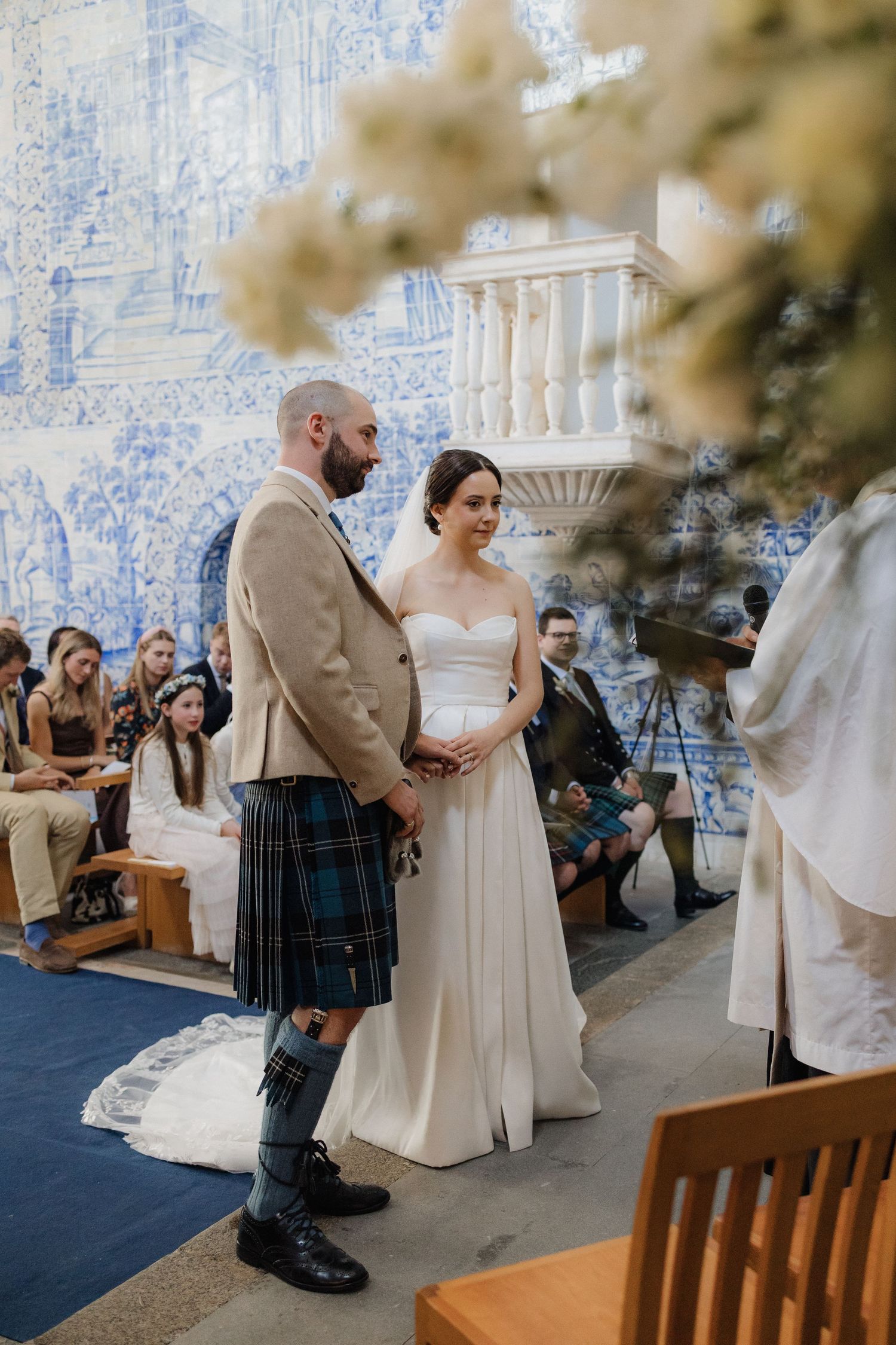 Couple exchanging vows in front of ornate blue and white azulejo tile walls.