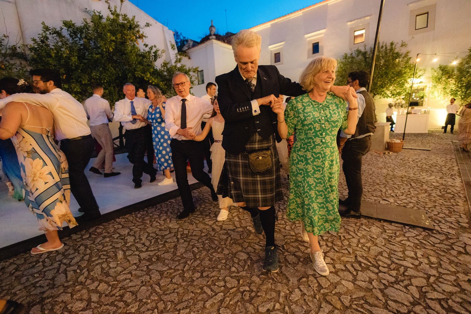 Outdoor wedding reception with guests mingling on a cobblestone patio.