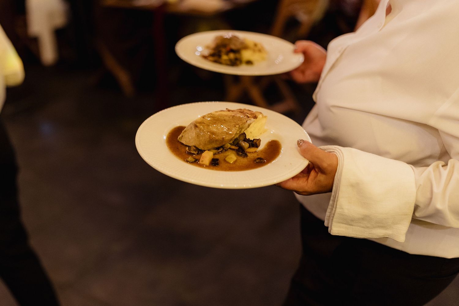 Restaurant staff serving plated meals during an evening event.