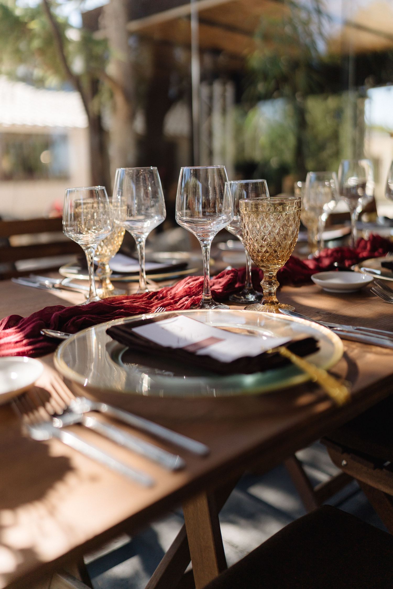 Sunlit wedding reception table with elegant place settings and crystal stemware.