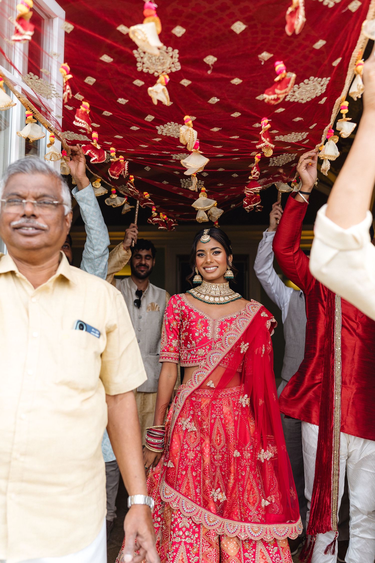 Wedding guests celebrate by throwing red flower petals during a traditional Indian wedding ceremony.