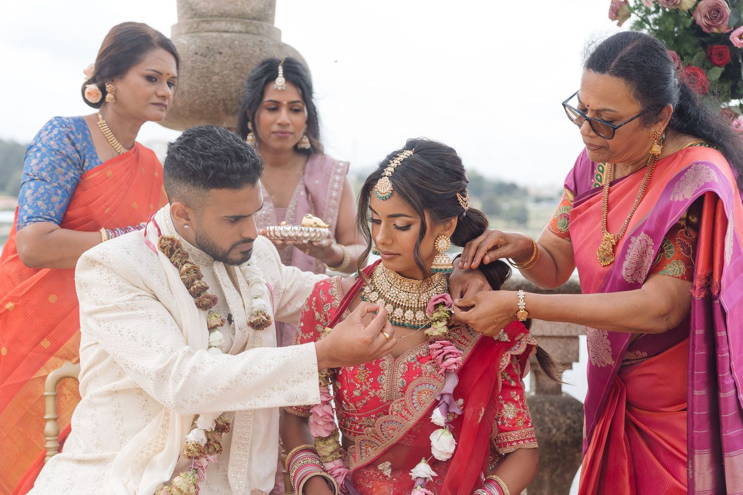 Traditional Indian wedding ceremony with family members performing rituals outdoors.