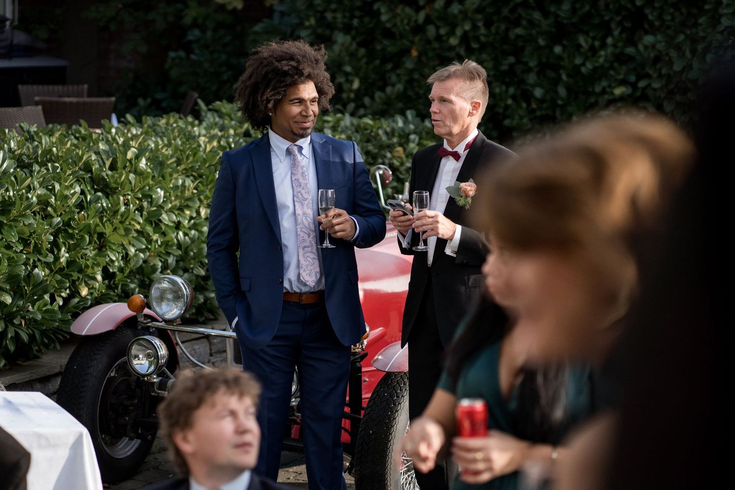 Wedding guests mingle and socialize at an outdoor garden reception.