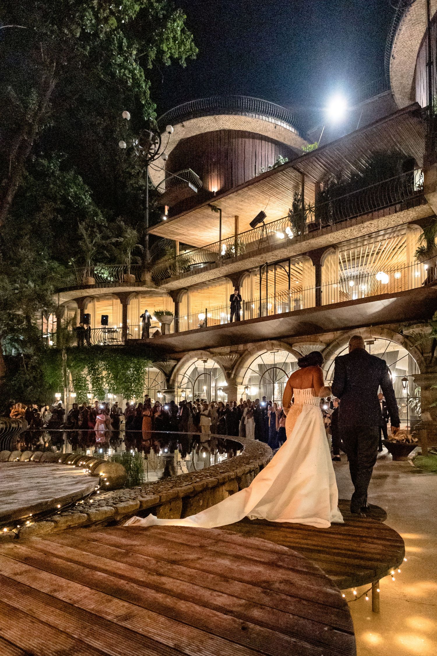 Night shots of a grand illuminated venue with arched walkways during a wedding celebration.