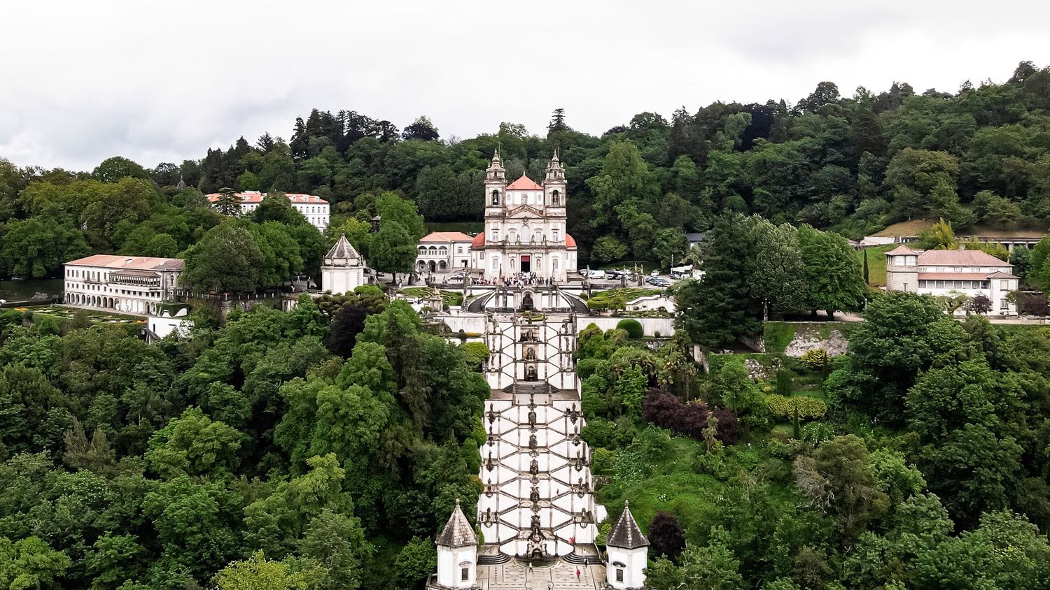 Panoramic view of hillside houses and buildings nestled among lush green trees.