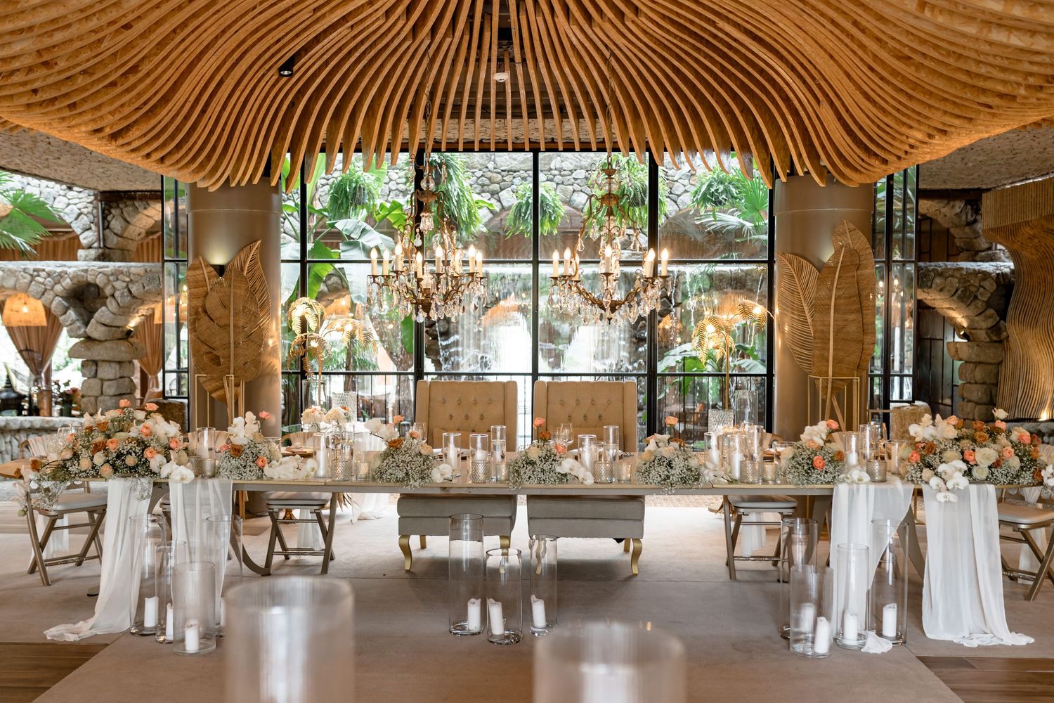 An elegant wedding reception venue with wooden beams and crystal chandeliers.