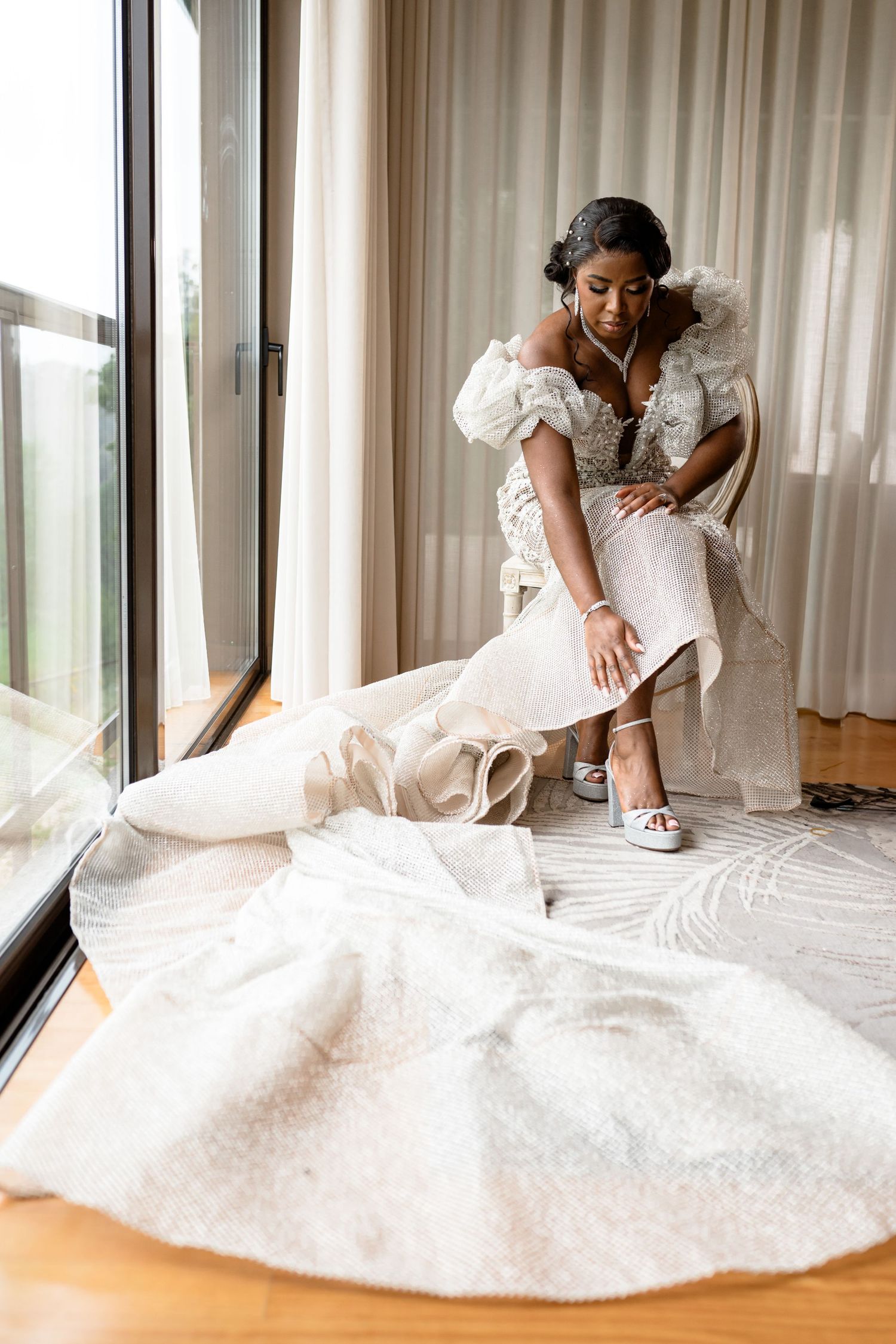 Wedding dress details with intricate lace and beading shown as bride adjusts her gown.