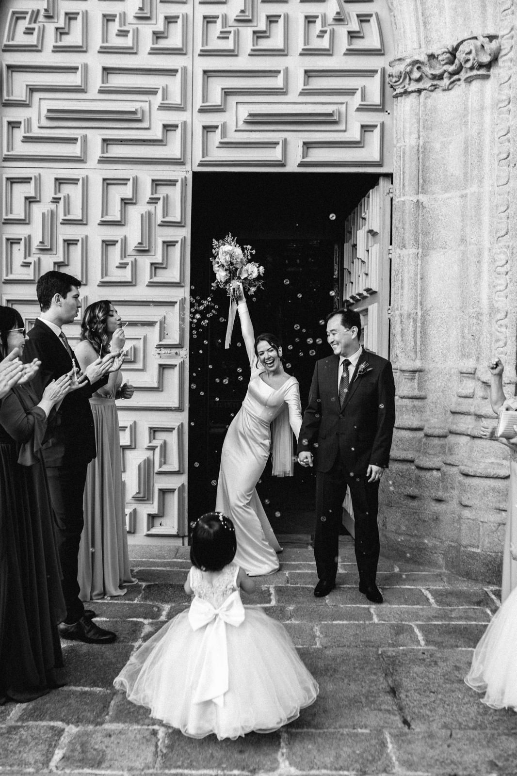 A series of four black and white wedding photos showing moments outside a church with ornate doors and stone walls.