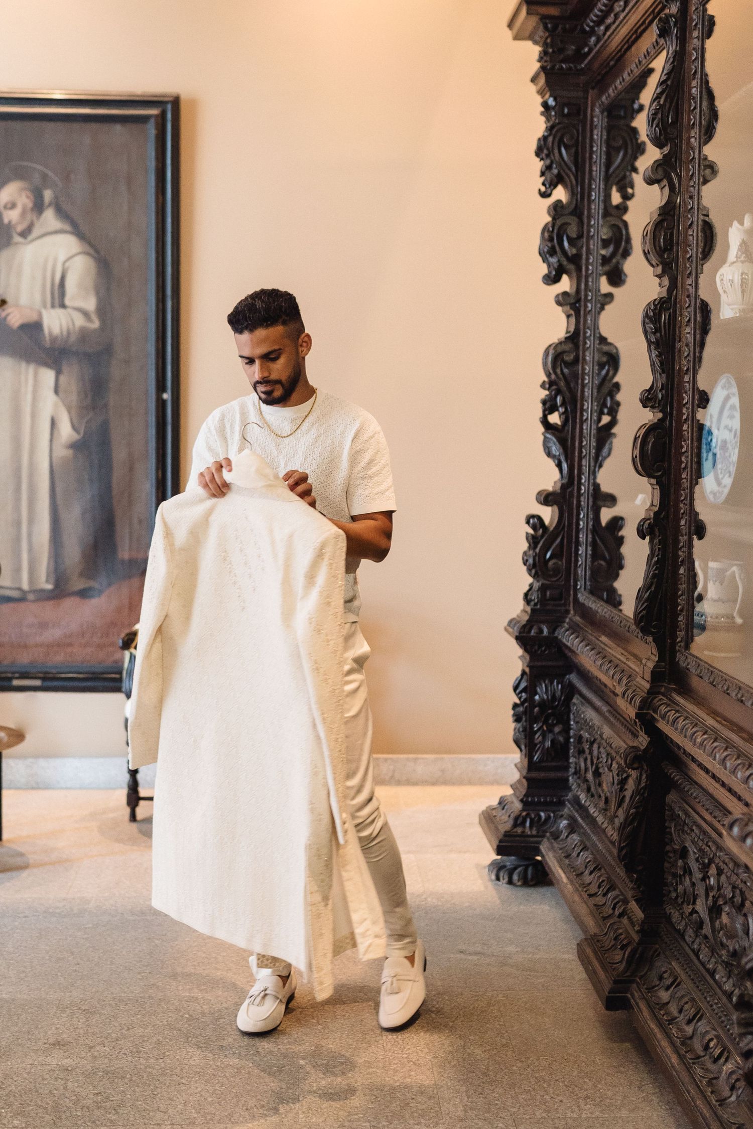 Fashion photoshoot in front of an ornate black mirror frame showing flowing white garments and minimalist styling.