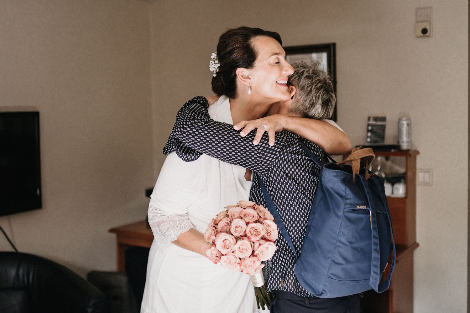 Two people embrace and dance together in a room with natural lighting.