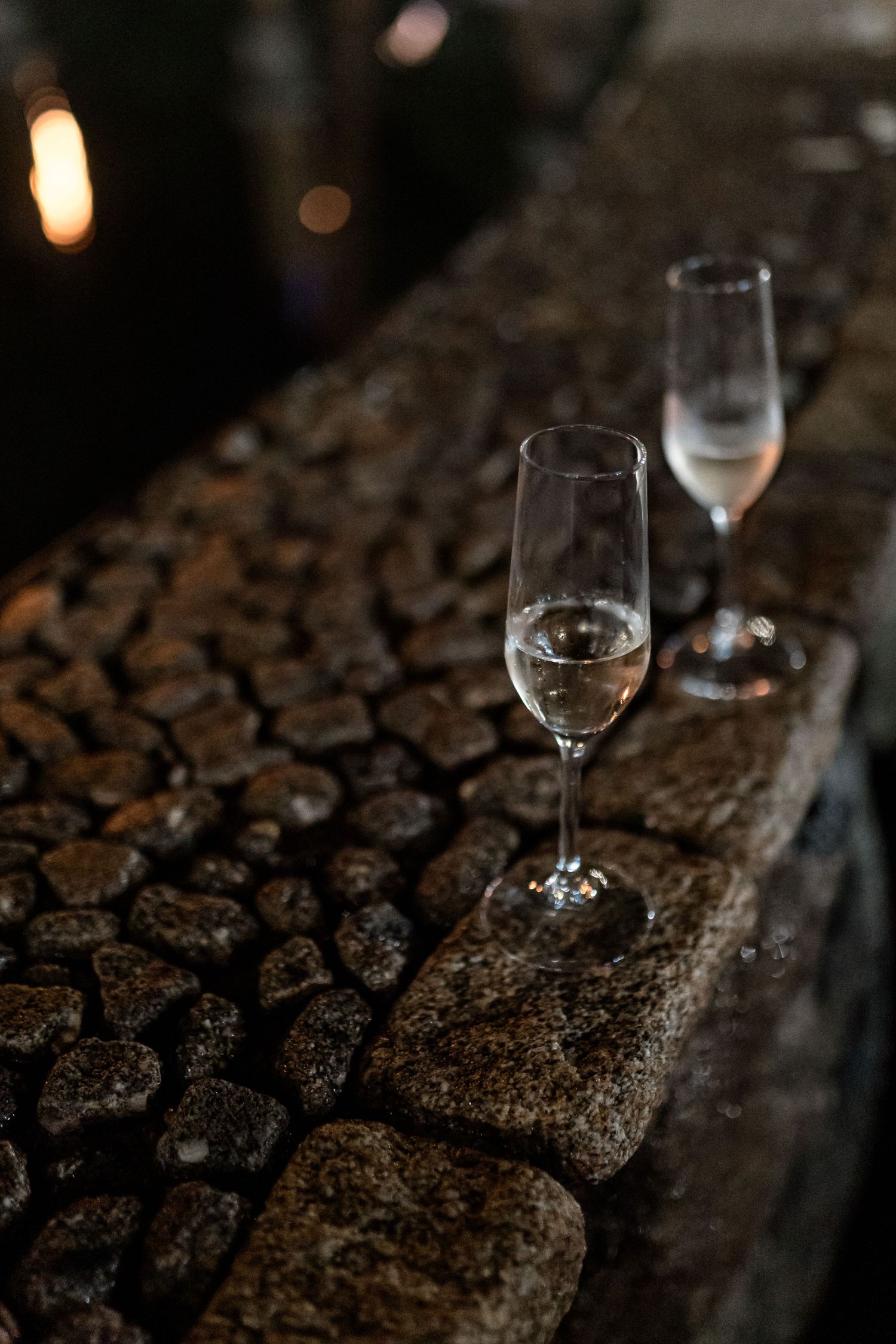 Wine glasses arranged on textured dark surface with ambient lighting.