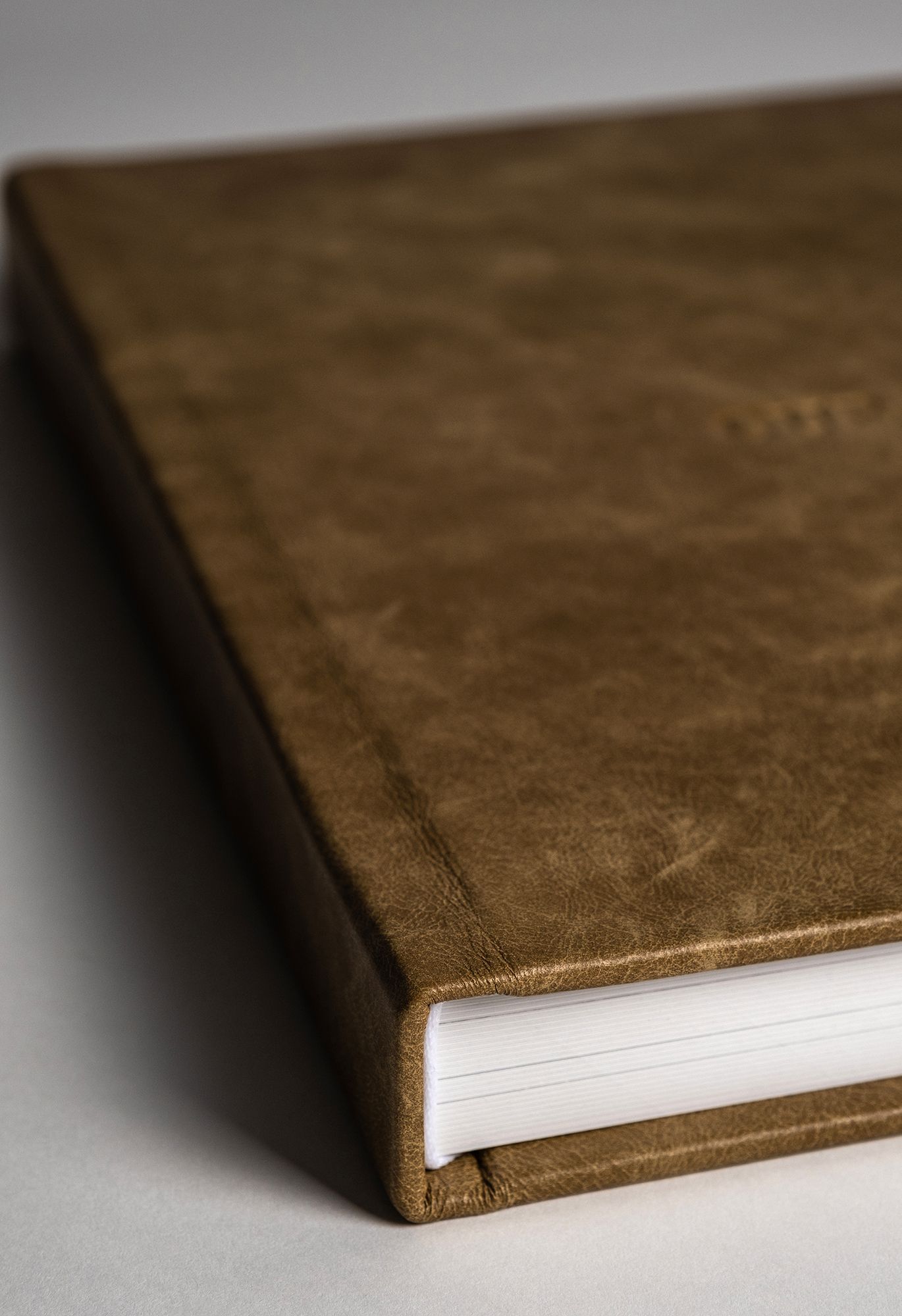 A close-up sequence of brown leather book covers showing varying depths and textures in a minimalist composition.