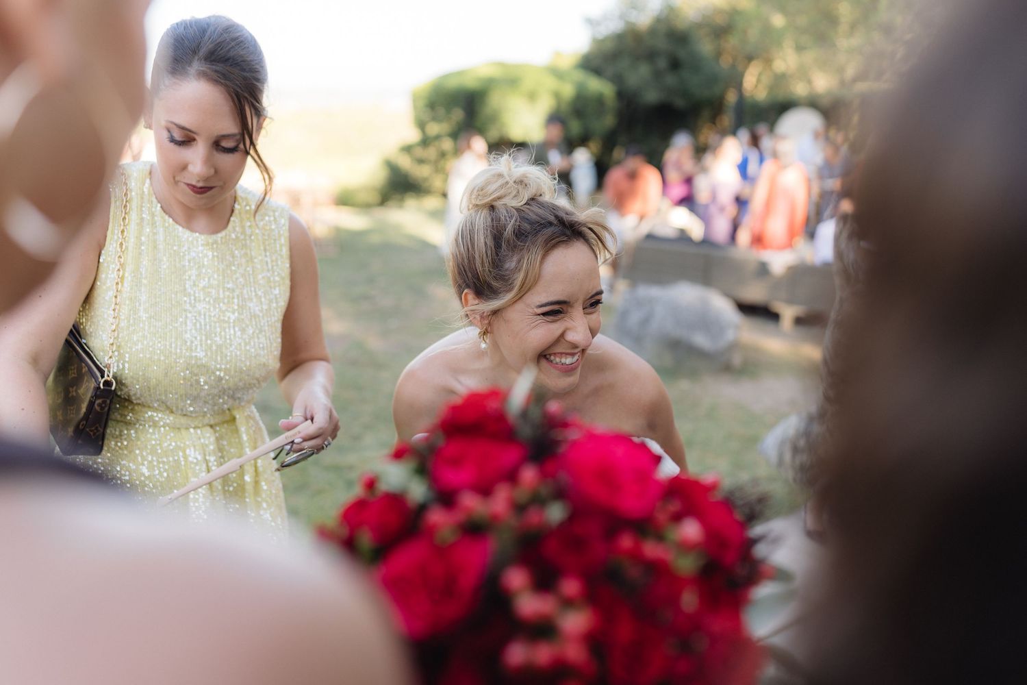 Candid moments shared between wedding party members with red floral accents.