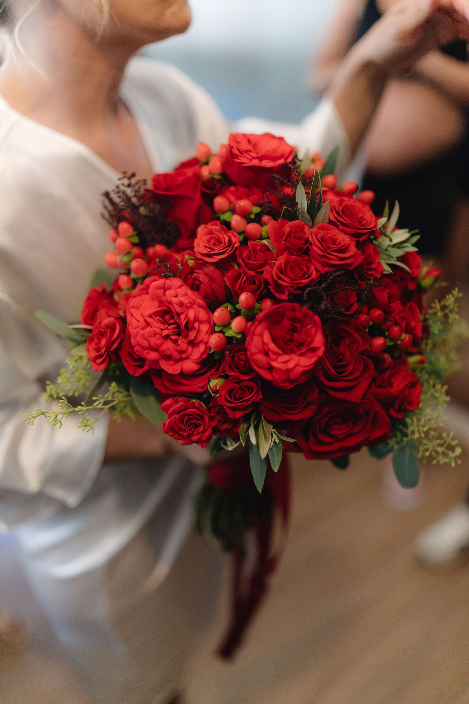 Stunning bouquet of deep red roses with greenery and burgundy ribbons.