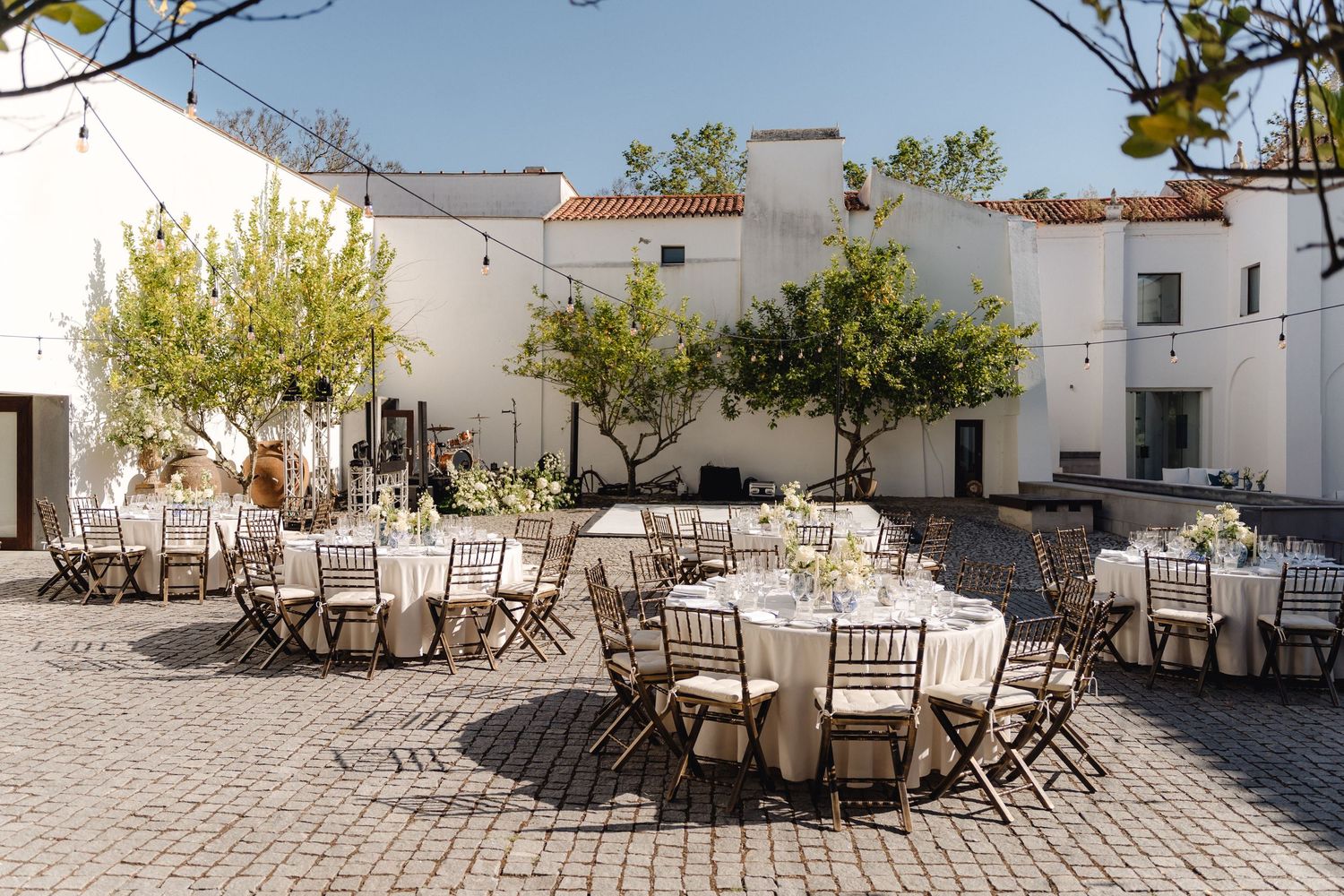 Outdoor wedding reception venue with round tables and chairs set up on a stone patio.