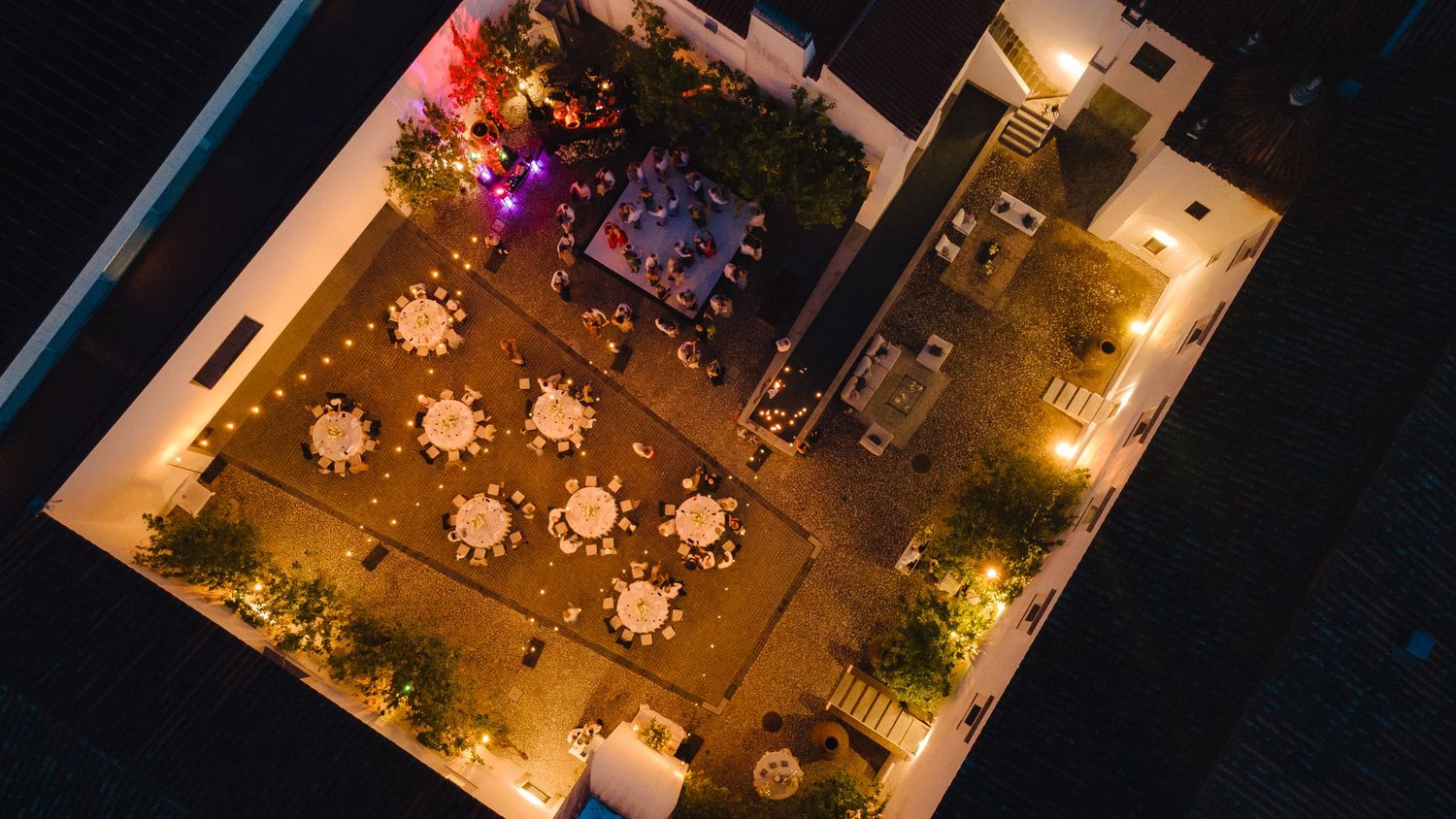 Aerial night view of an illuminated outdoor event space with purple lighting.