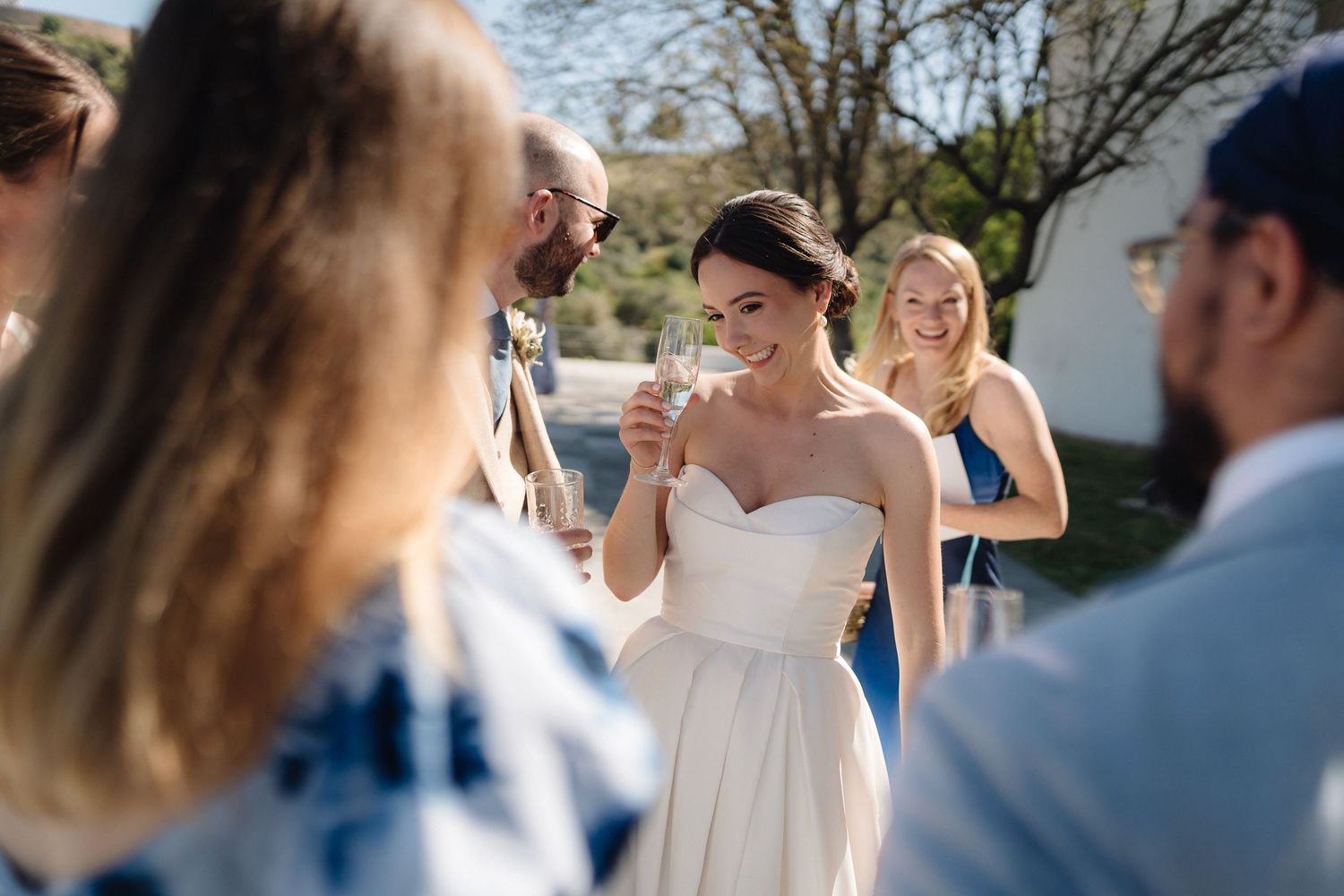 Guests celebrate at an outdoor wedding reception with joyful expressions.