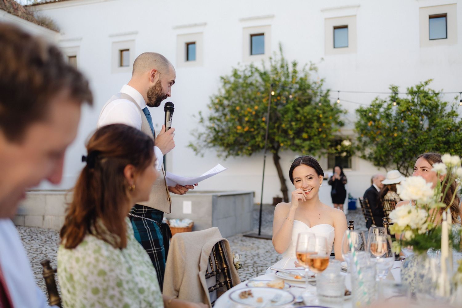 Elegant outdoor wedding reception setup against white Mediterranean-style architecture.