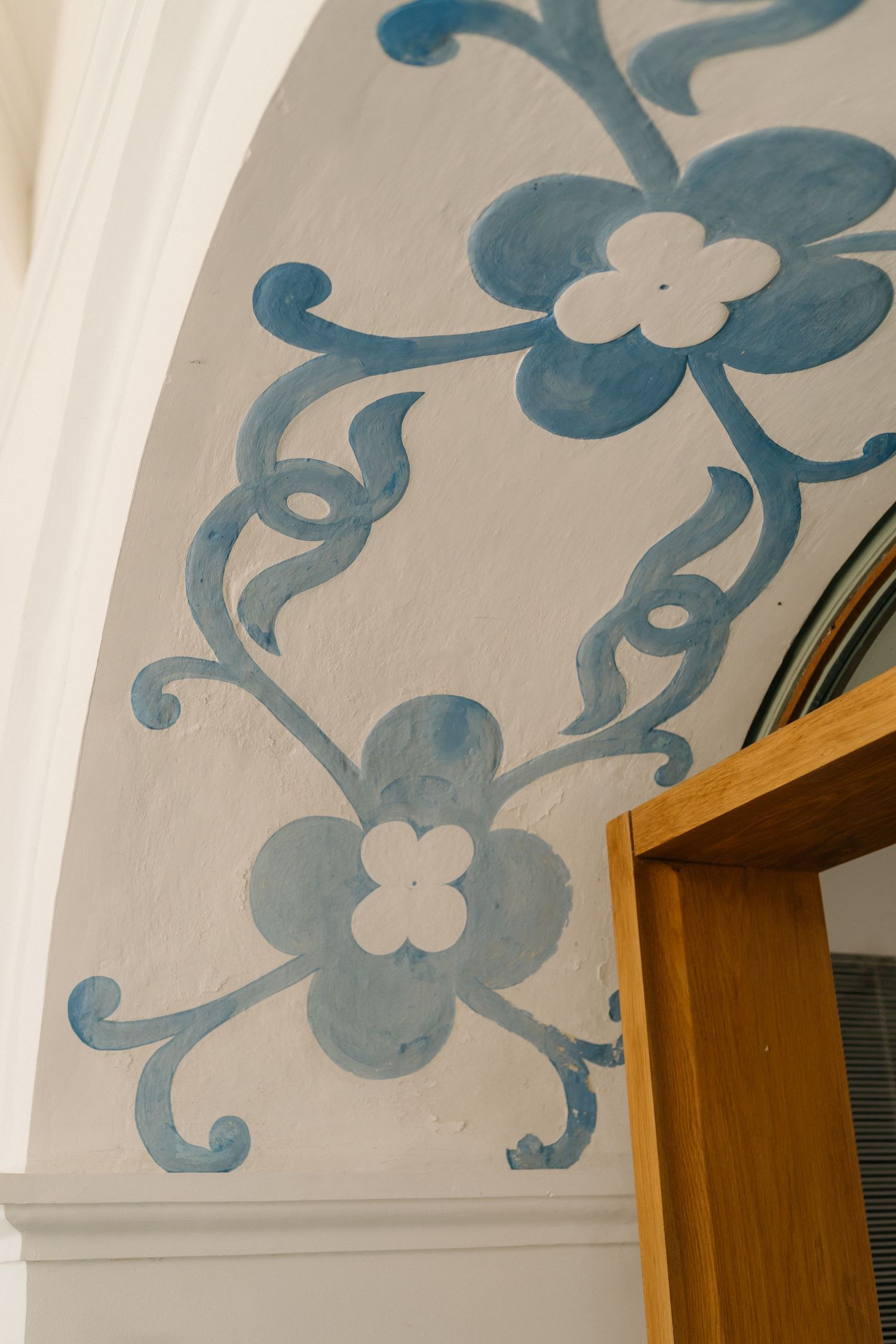 Decorative blue floral patterns painted on a white ceiling with wooden door frame visible.