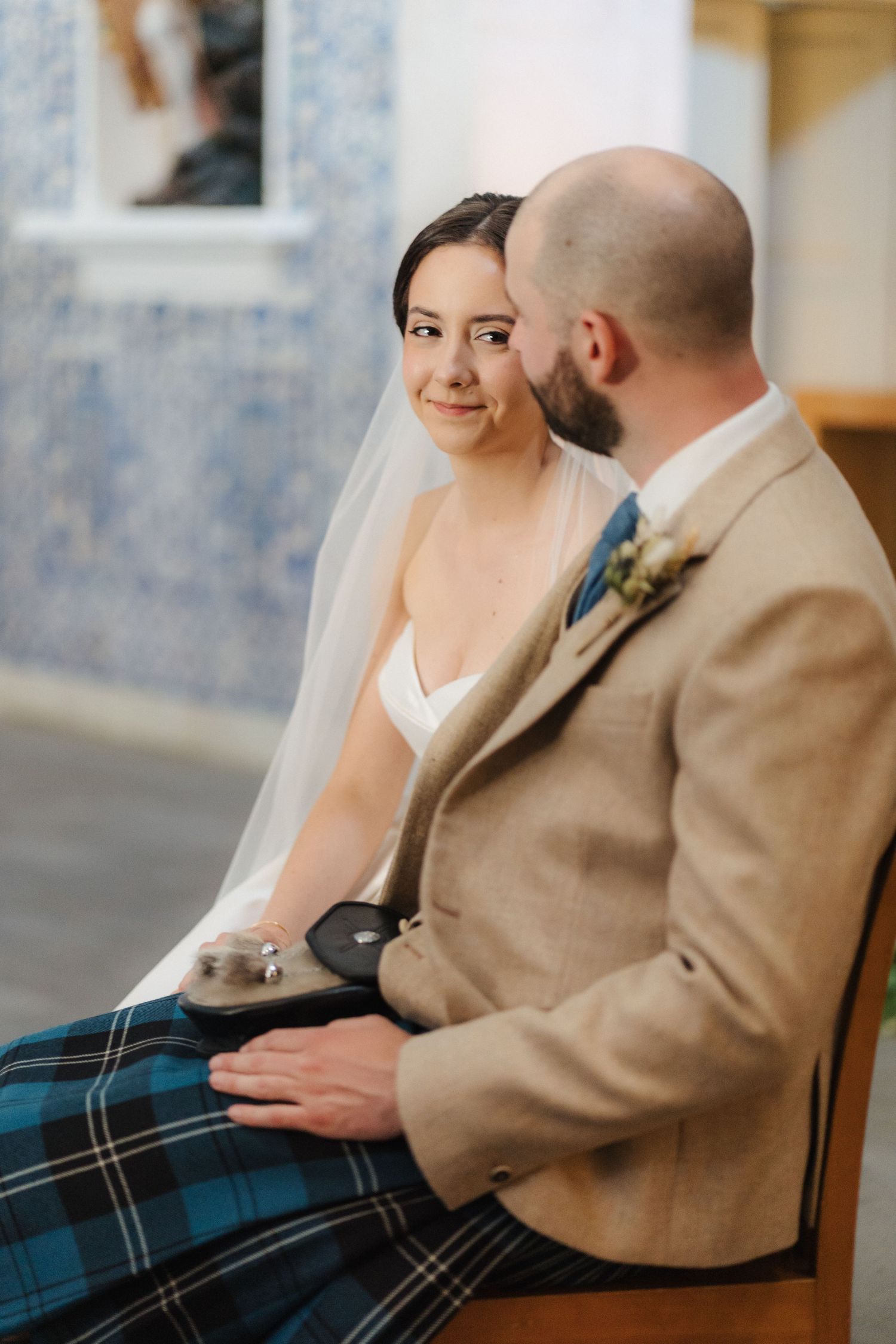 Intimate wedding ceremony moment in a chapel with traditional Scottish tartan details.
