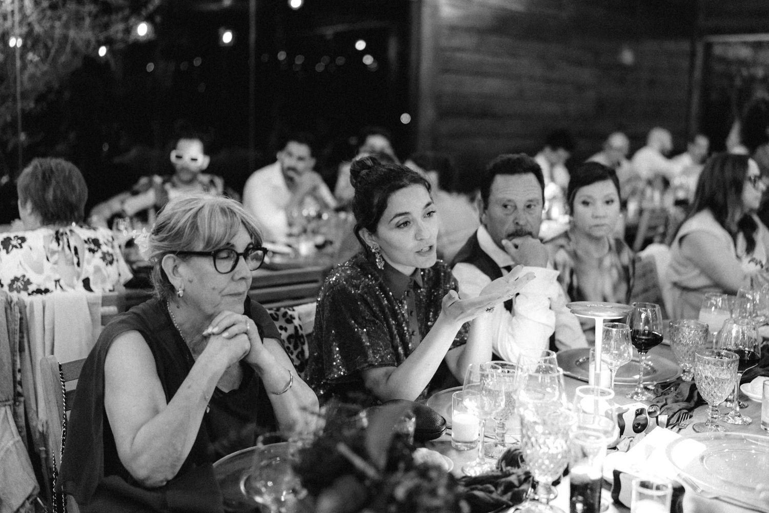Black and white photo of dinner guests enjoying conversation at a formal event.