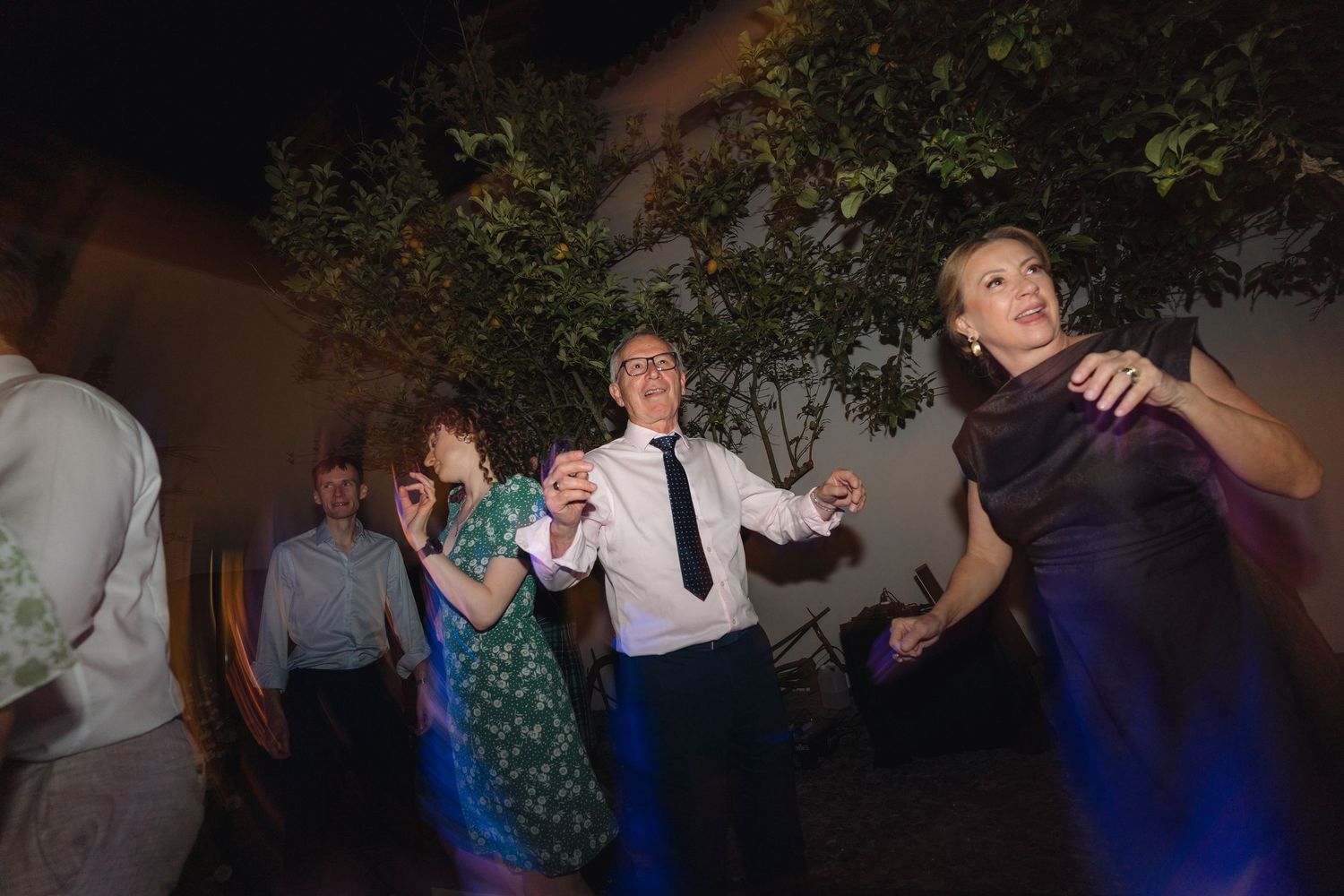Wedding reception guests dancing and enjoying themselves in a dimly lit venue.
