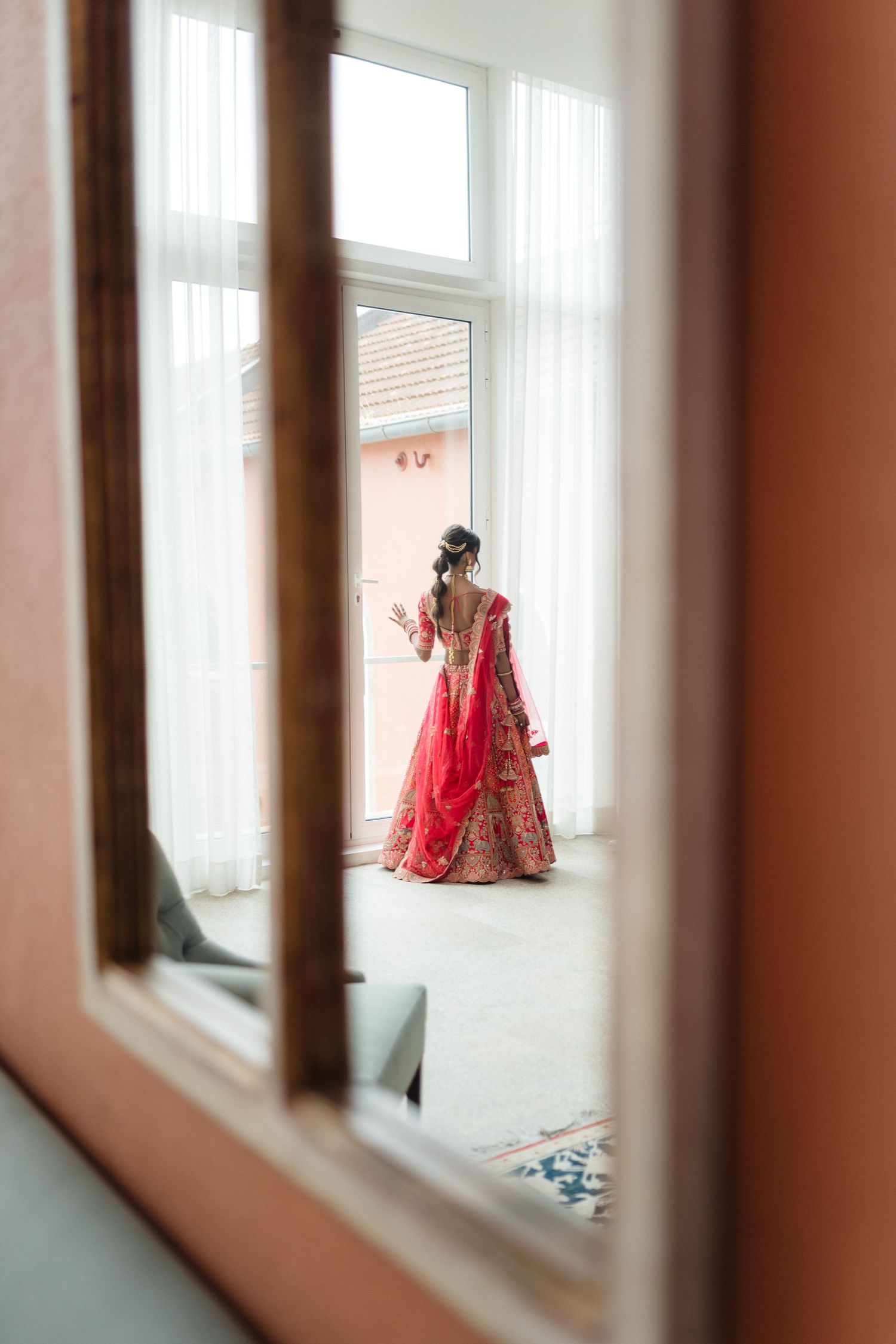 Artistic window frame composition showing glimpses of red formal attire.