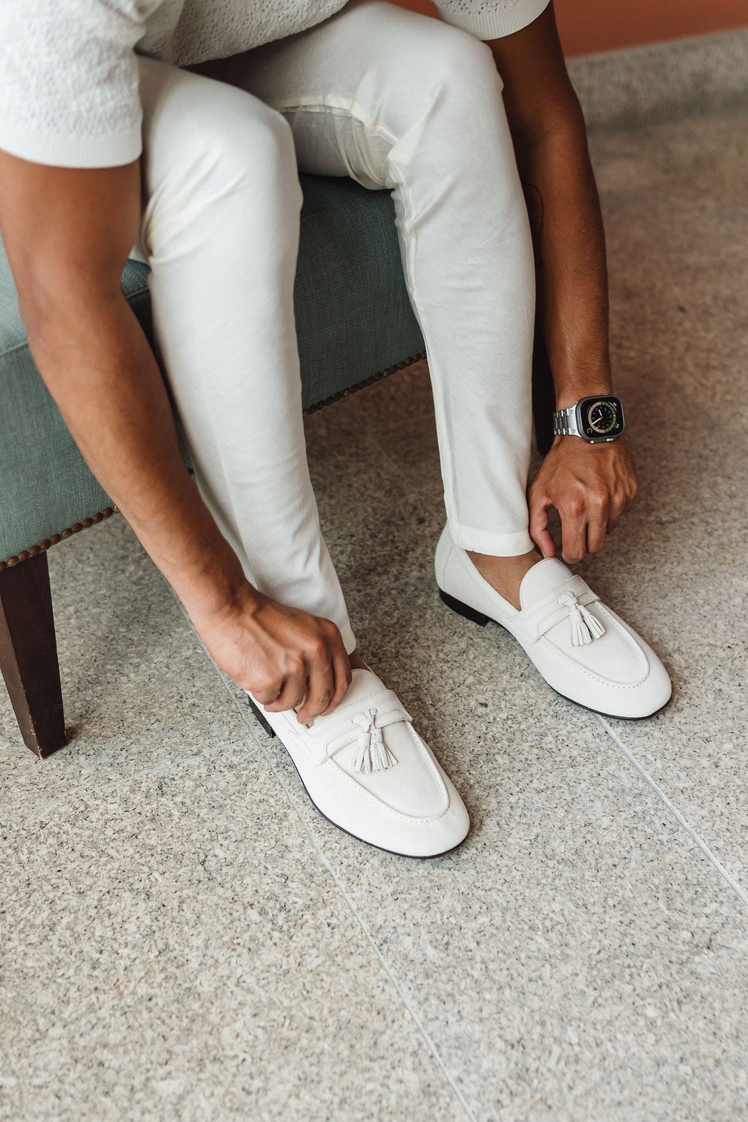 Close-up of white formal loafers being put on against a grey floor.