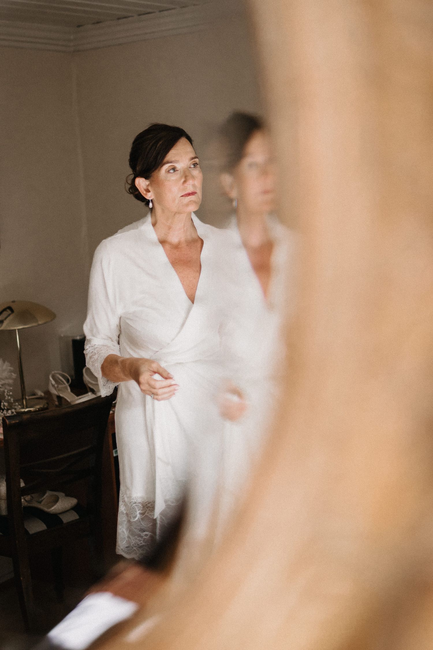 Woman in white robe getting ready in a softly lit room.