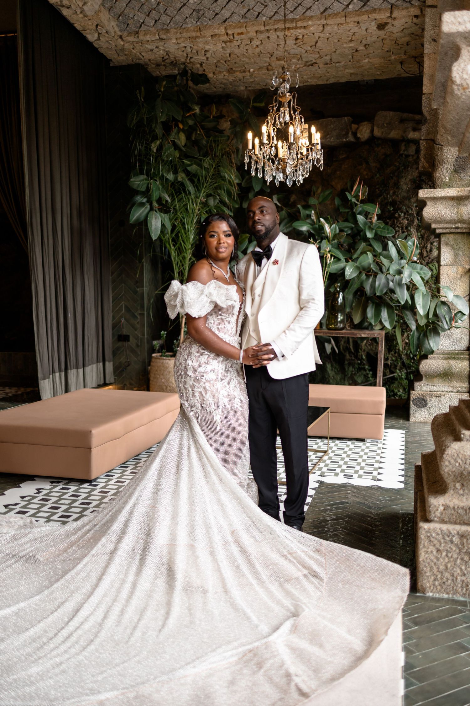 A dramatic wedding dress with long train displayed in an ornate stone corridor.