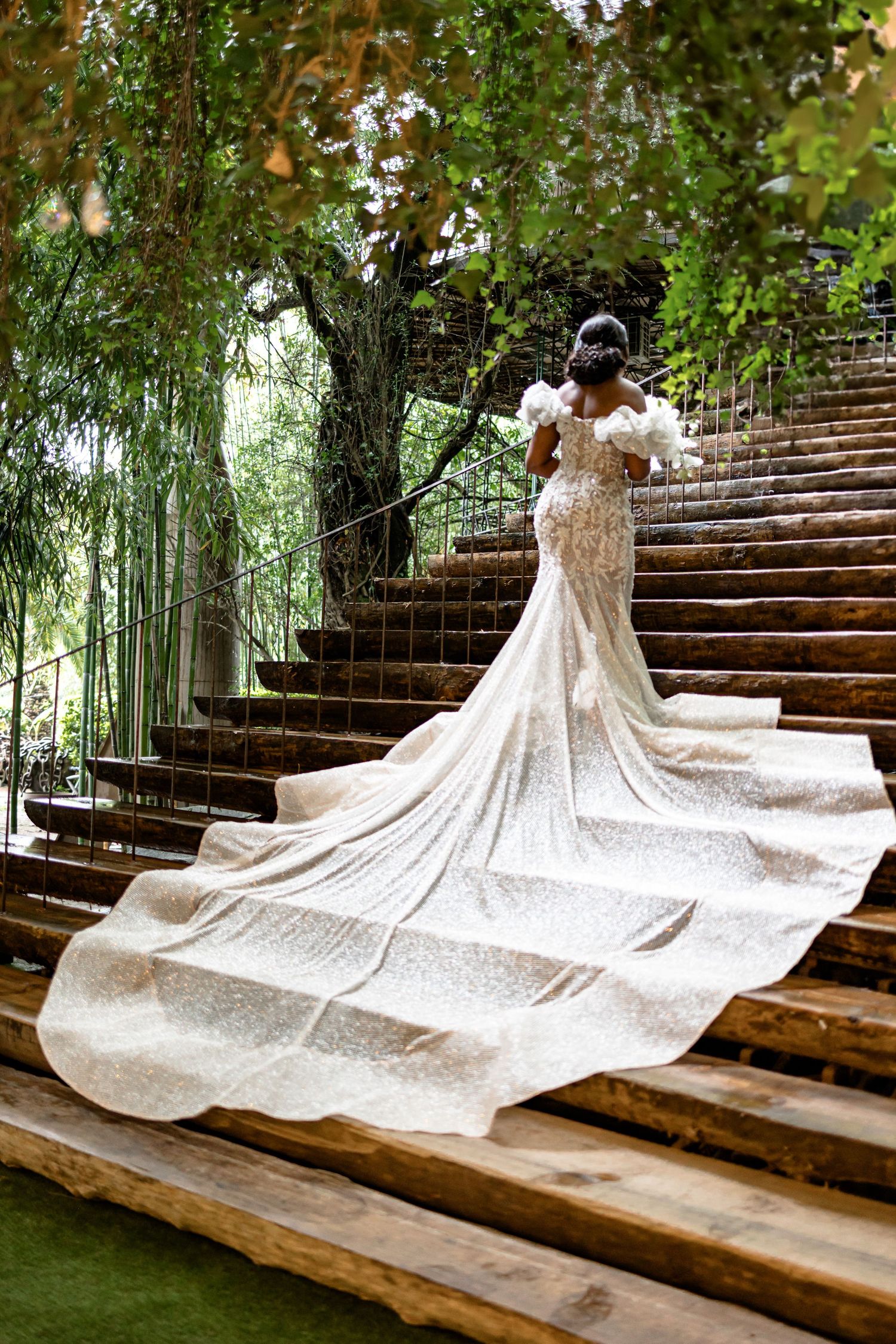 Dramatic wedding dress with long train spread across outdoor garden steps.