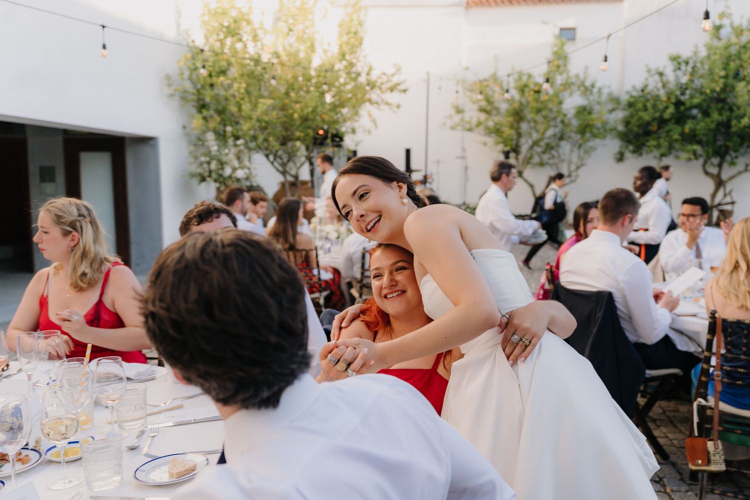 Guests mingling at outdoor tables during a sunny wedding reception.