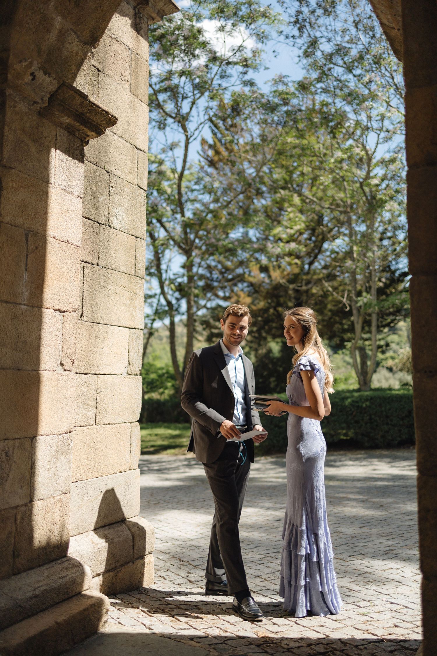 Couple sharing a private moment under stone archways in a garden setting.