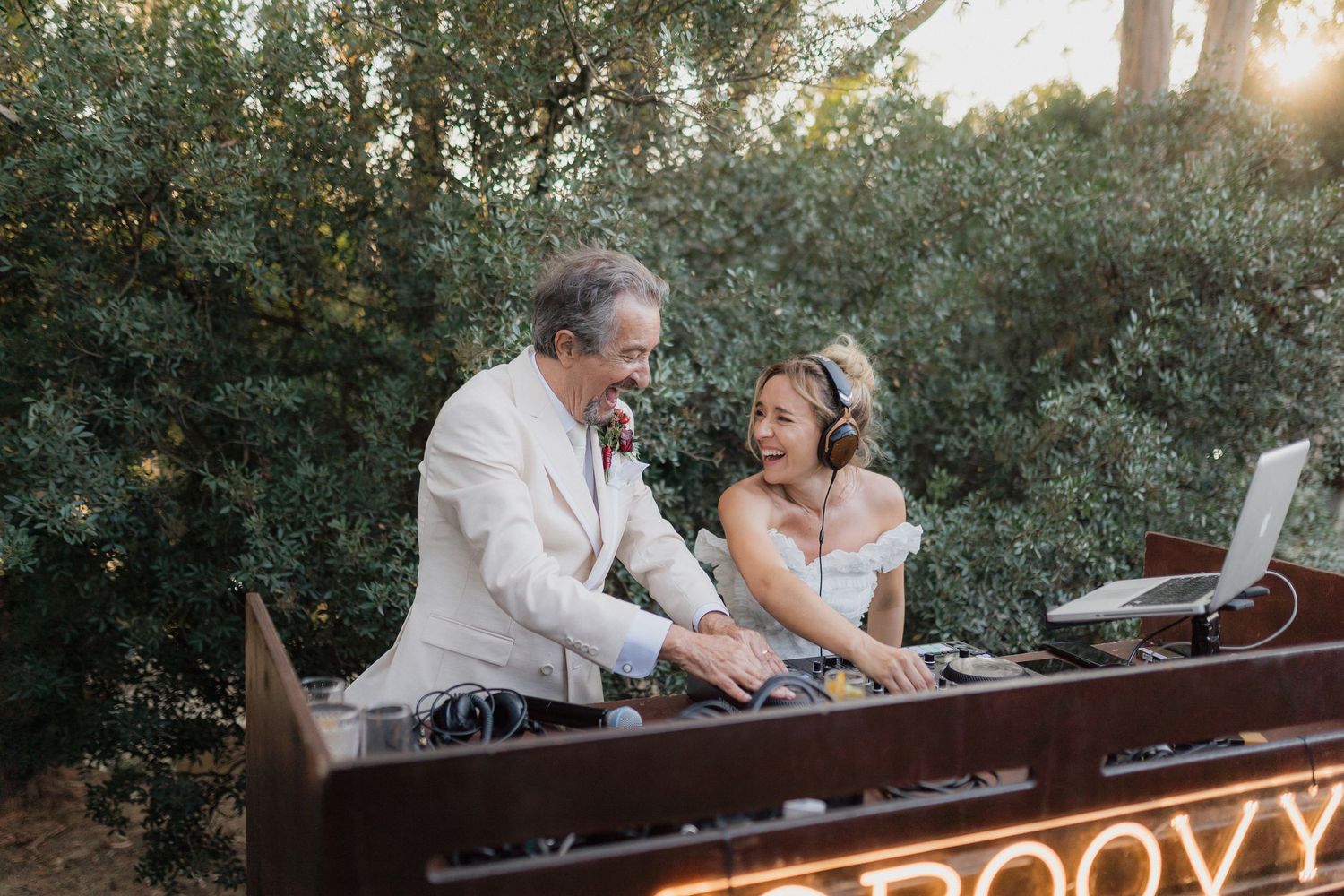 Wedding DJs sharing a fun moment while performing at outdoor reception.