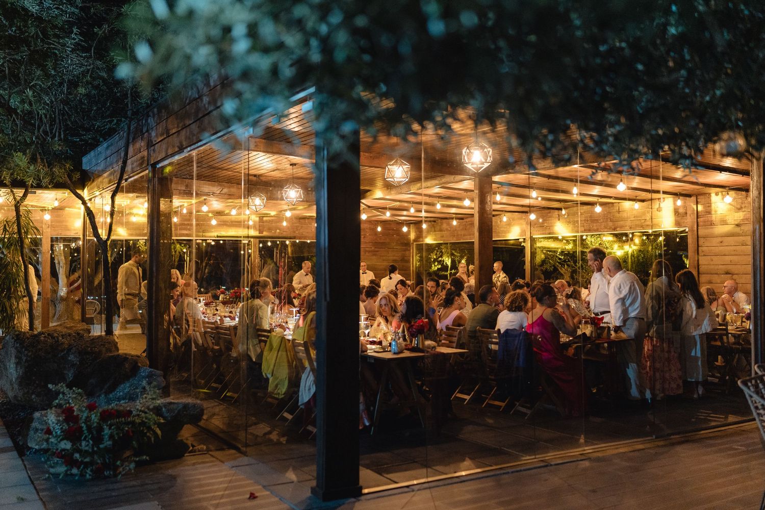 Panoramic view of an outdoor evening venue with string lights and dining tables.