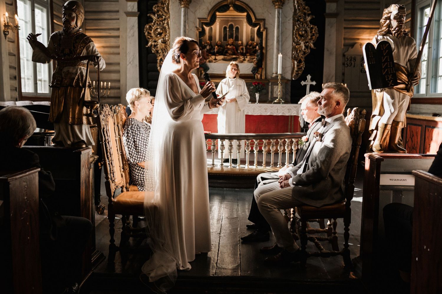 Wedding ceremony inside historic church with dramatic lighting and architectural details.