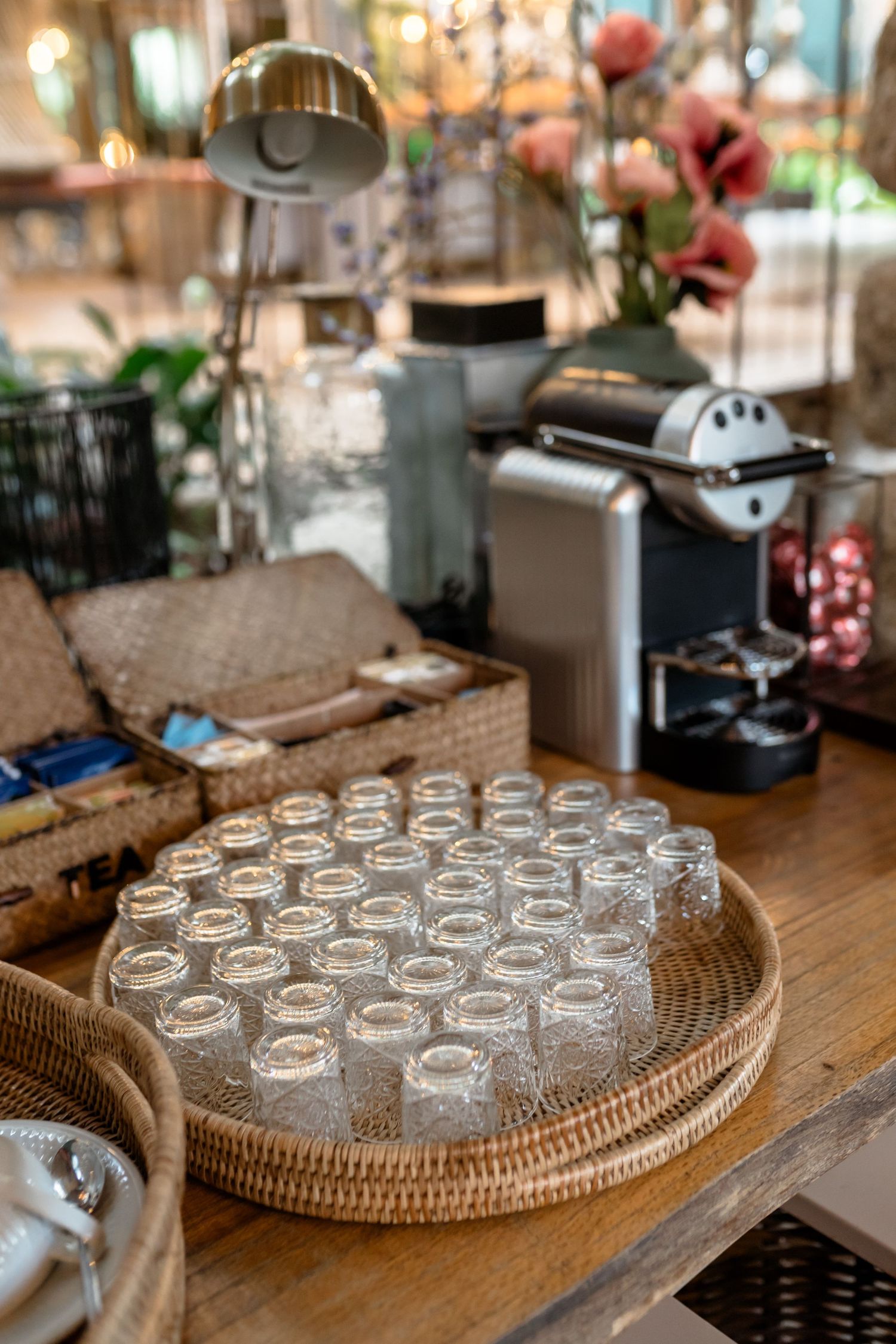 Multiple empty glasses arranged on a wooden surface with woven rattan placemats.