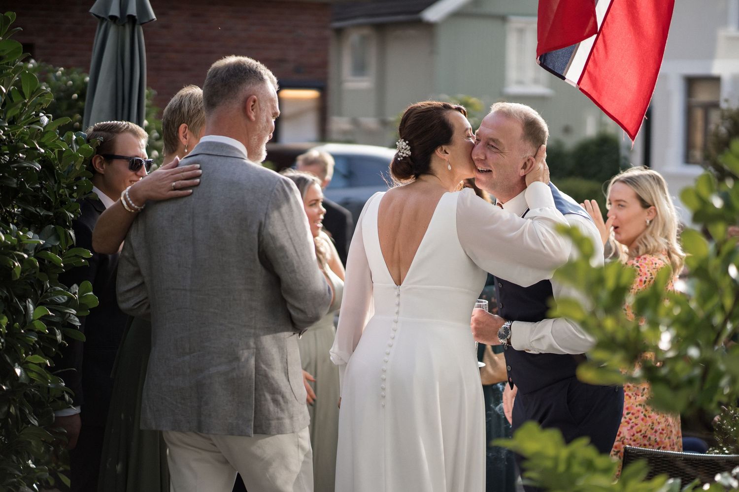 A wedding celebration outdoors with red flags and guests mingling in a garden setting.